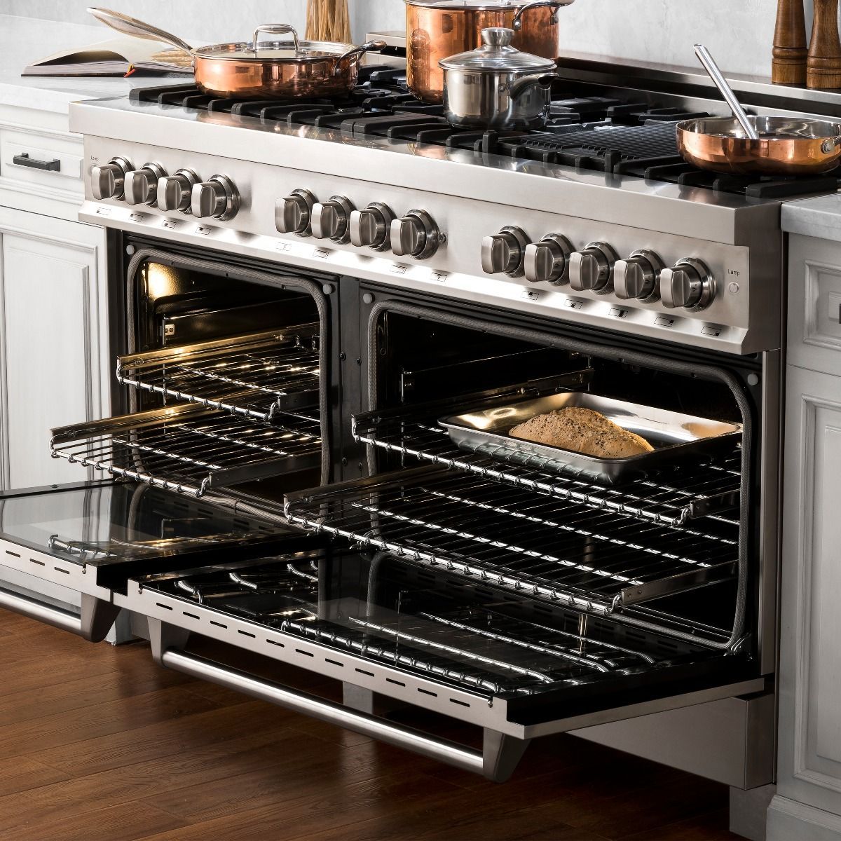Stainless range with oven door open, illuminated racks, and roasting pan