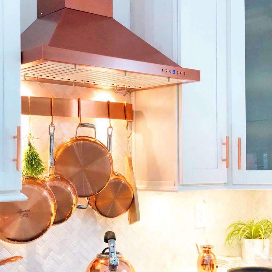 Copper-finish wall range hood underside with vent slats and control button strip