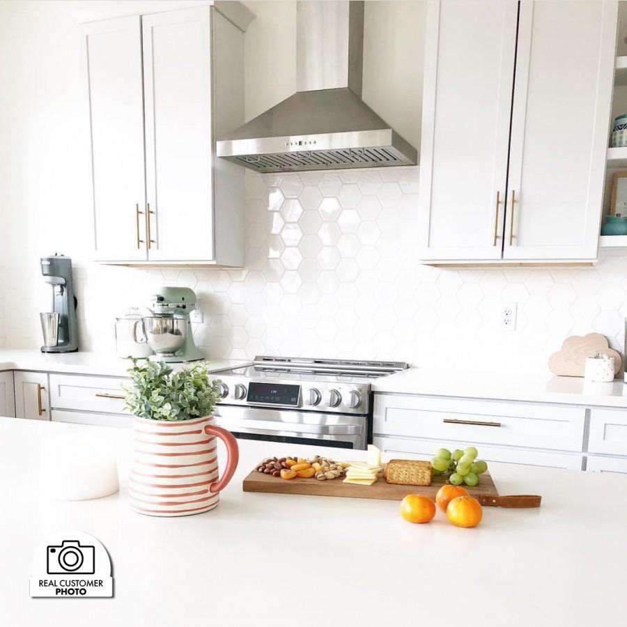 Stainless steel range hood above a cooktop in a bright kitchen setting