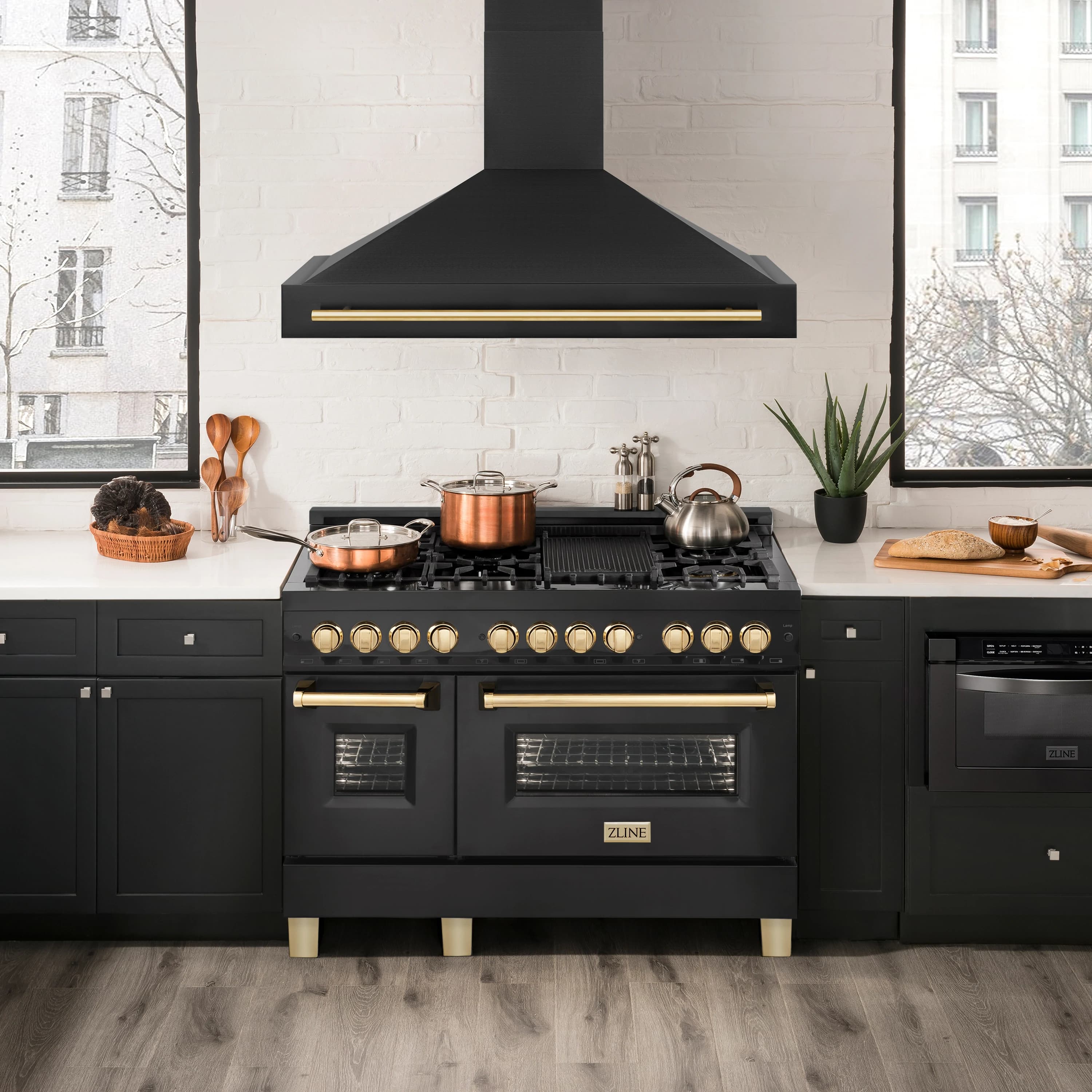 Black wall mount range hood above cooktop with gold handle bar