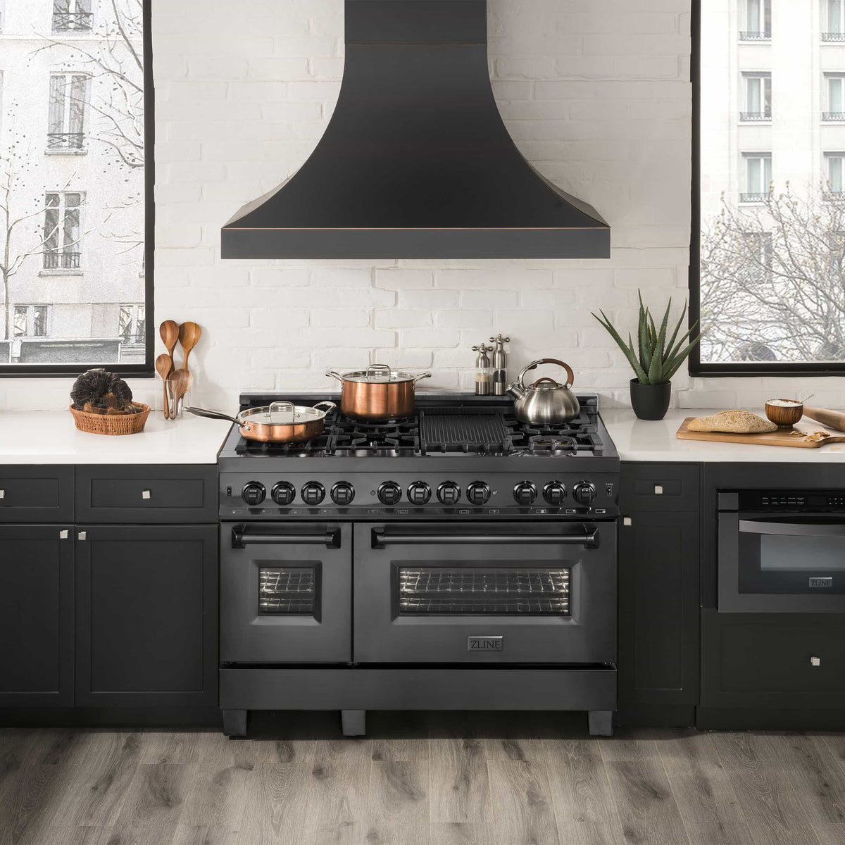 Black stainless dual fuel range with chimney hood and multiple brass gas burners