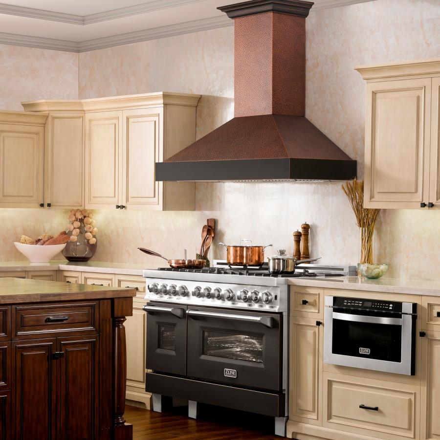 Hand-hammered copper wall range hood with dark chimney and vent canopy