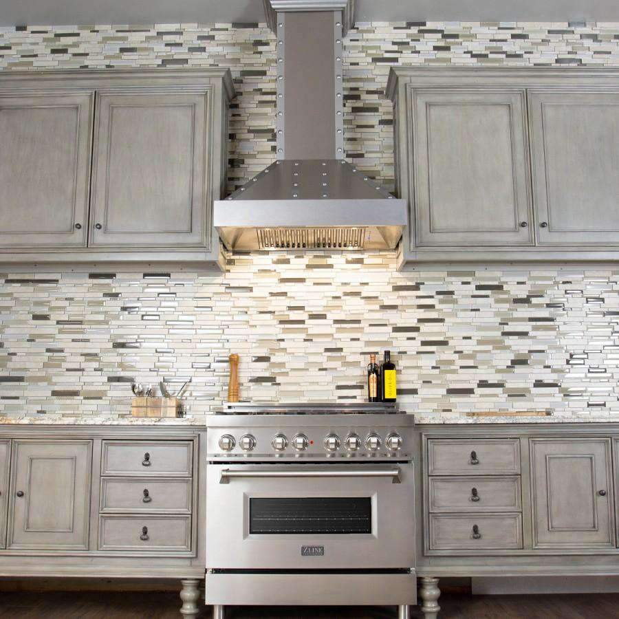Stainless steel chimney wall range hood centered above gas range and backsplash