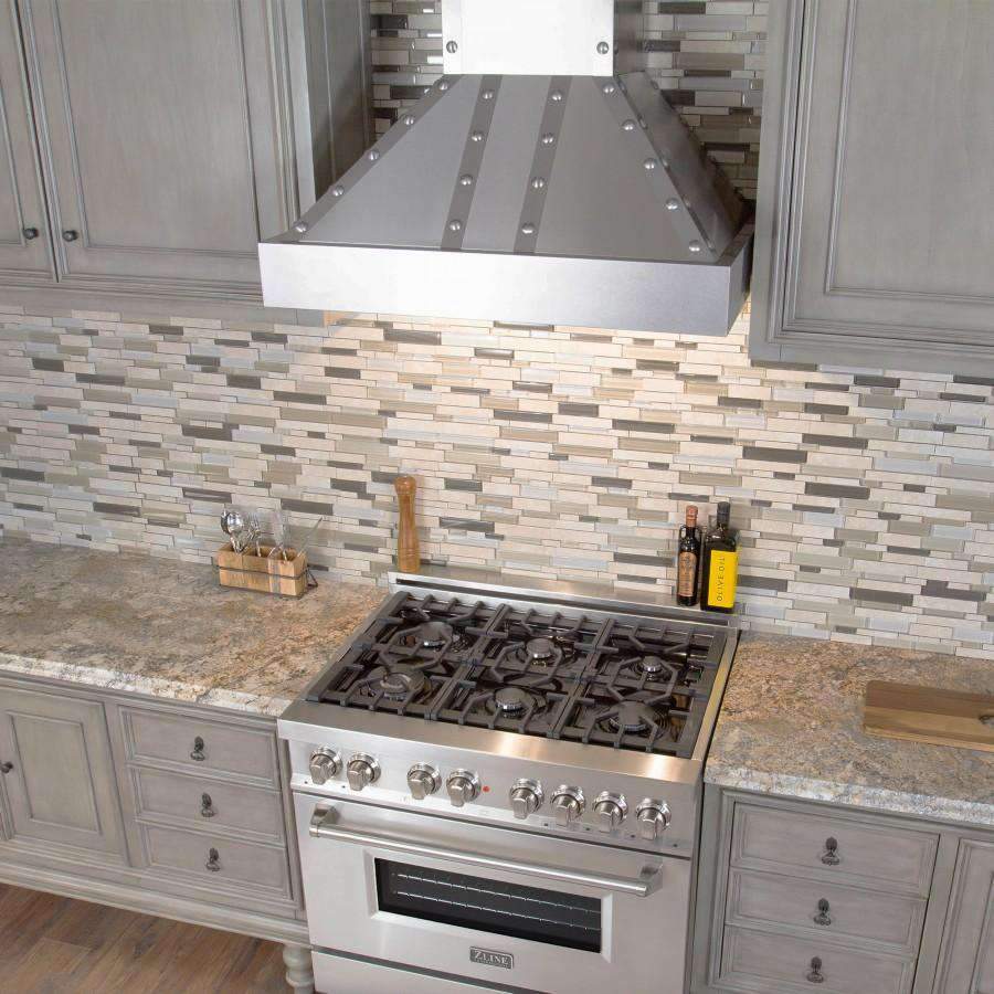 Stainless steel chimney wall range hood above gas cooktop on tiled backsplash