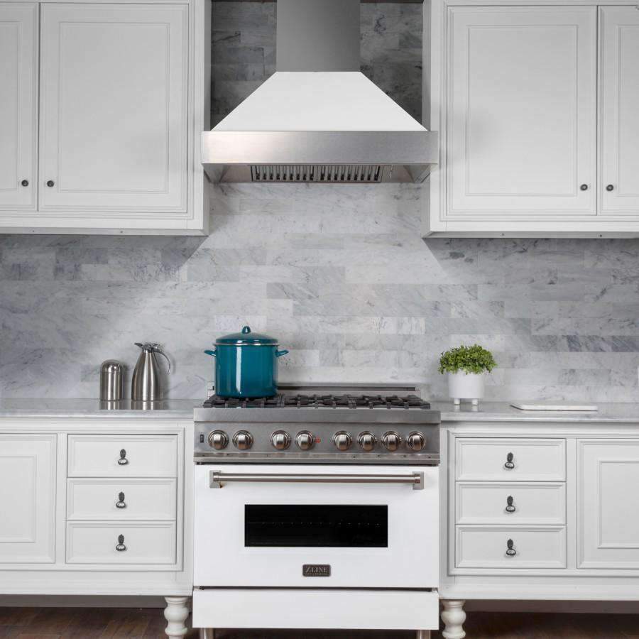 Wall-mount range hood with white matte shell and stainless chimney over a gas cooktop