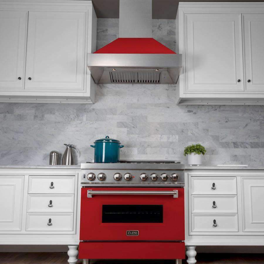 Red matte and stainless wall-mount range hood over a gas range with chimney canopy.