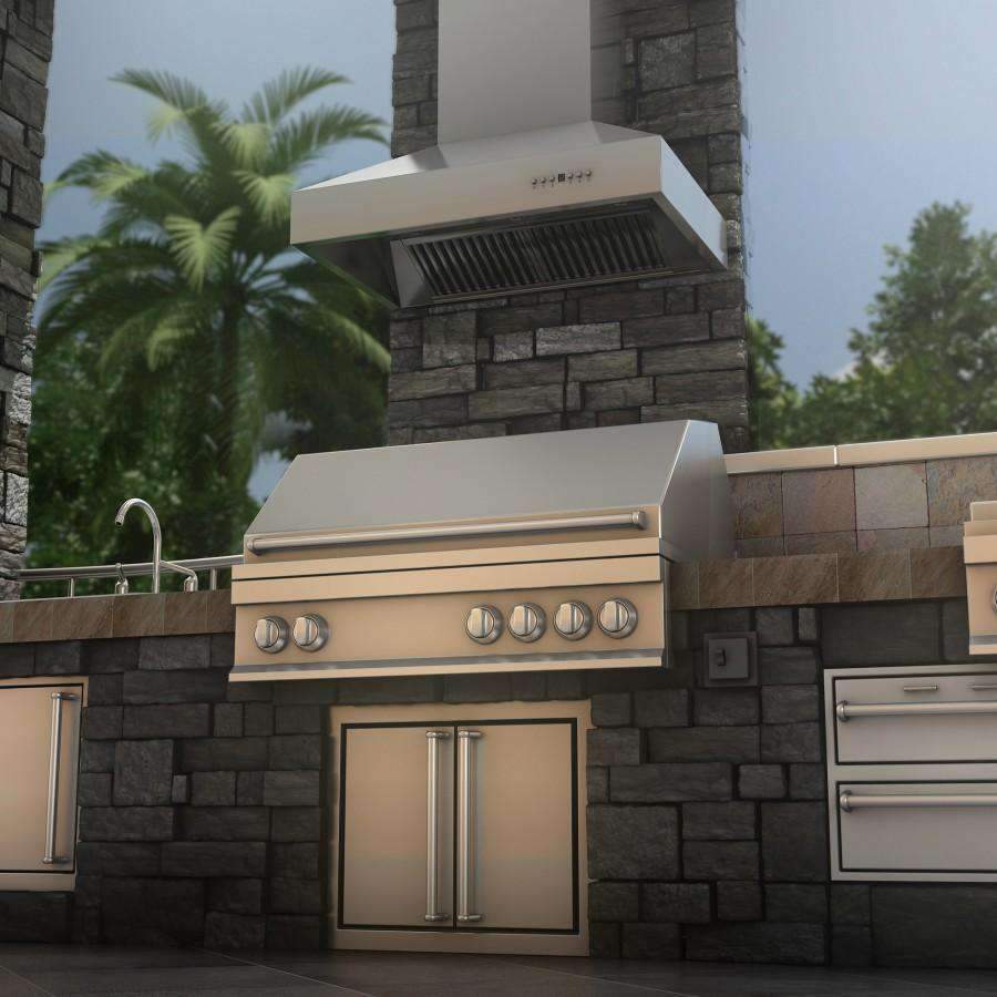 Outdoor stainless steel ducted wall mount range hood above a built-in outdoor grill