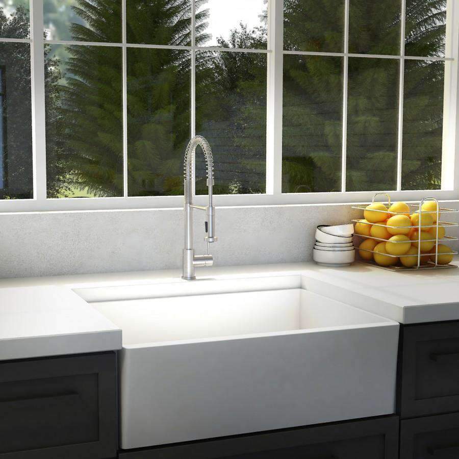 Brushed nickel kitchen faucet with arched spout and pull-down sprayer over sink.