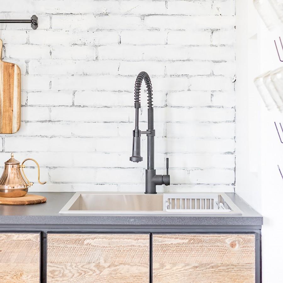 Matte black kitchen sink faucet with tall arched spout and coiled sprayer hoses