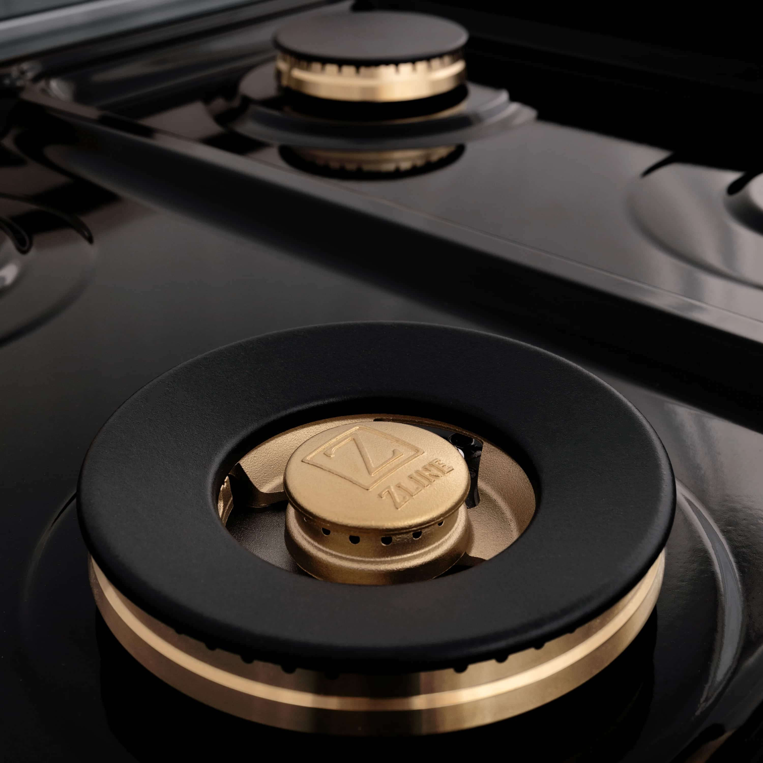 Two-piece appliance package: black cooktop burner with gold cap and ZLINE label