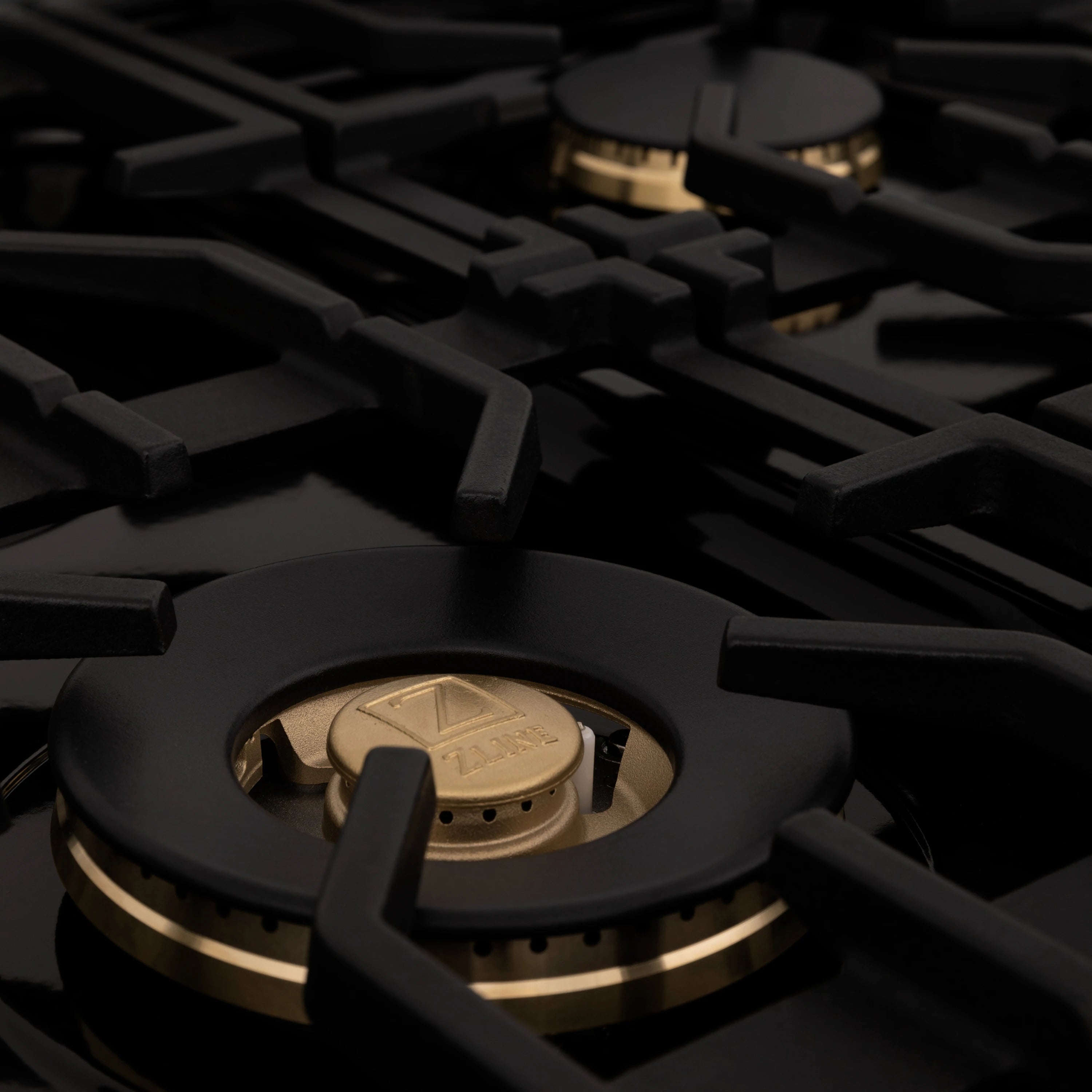 Gas burner head with gold ring detail on black cast-iron grate
