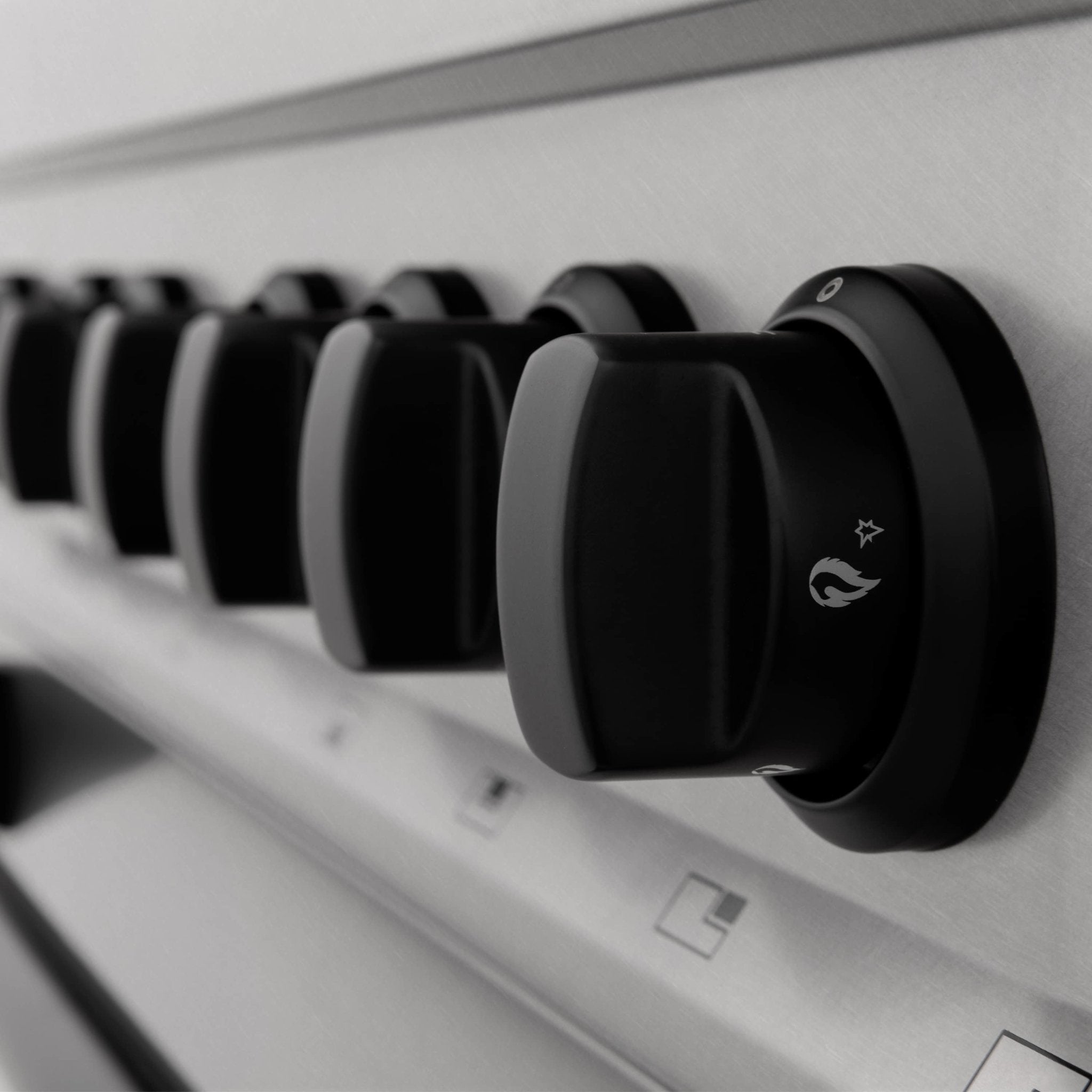 Row of black control knobs on white satin stainless steel control panel