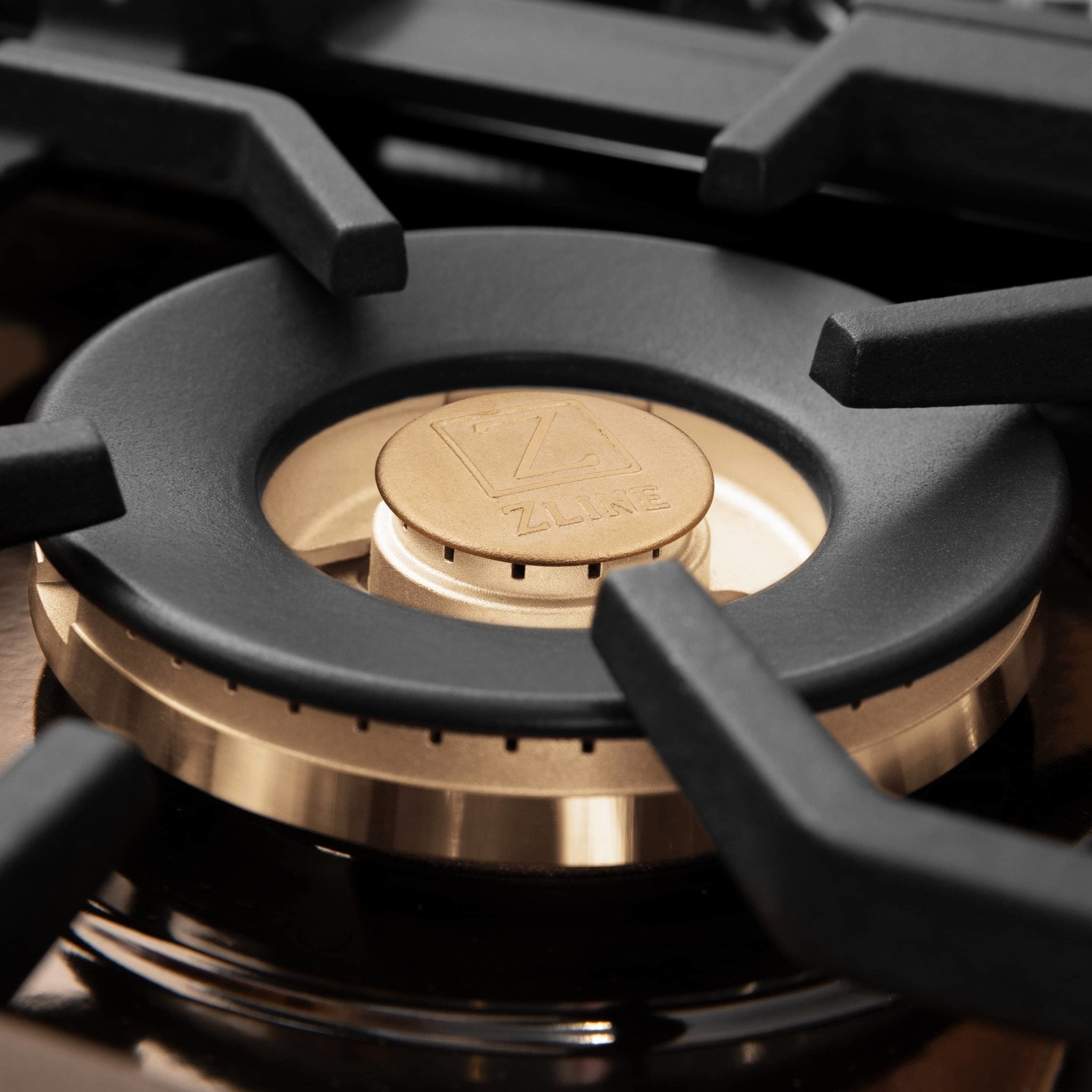 Close-up of dual-fuel range burner cap with black grate and brass trim ring