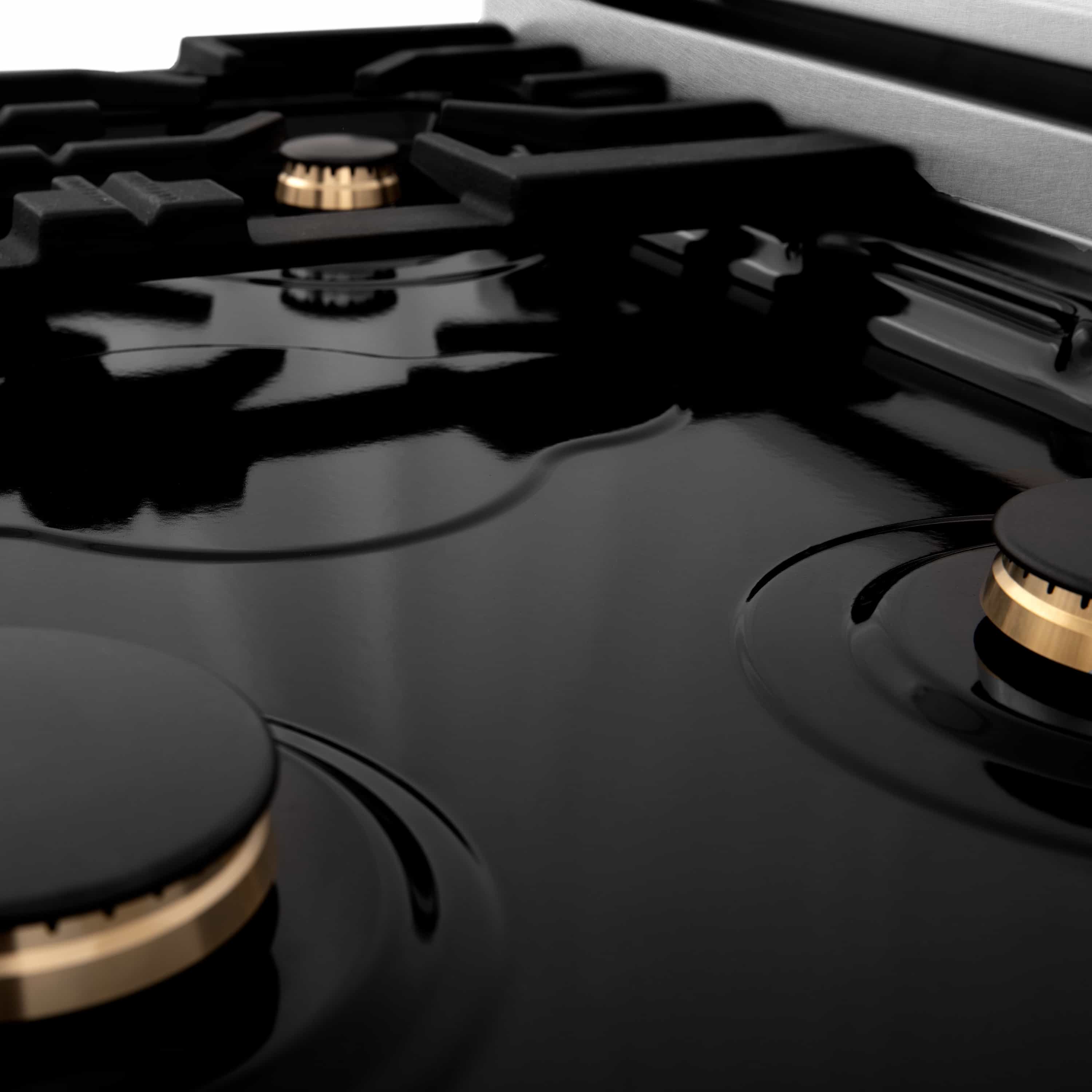 Black cooktop with multiple burner grates and gold-accent control knobs