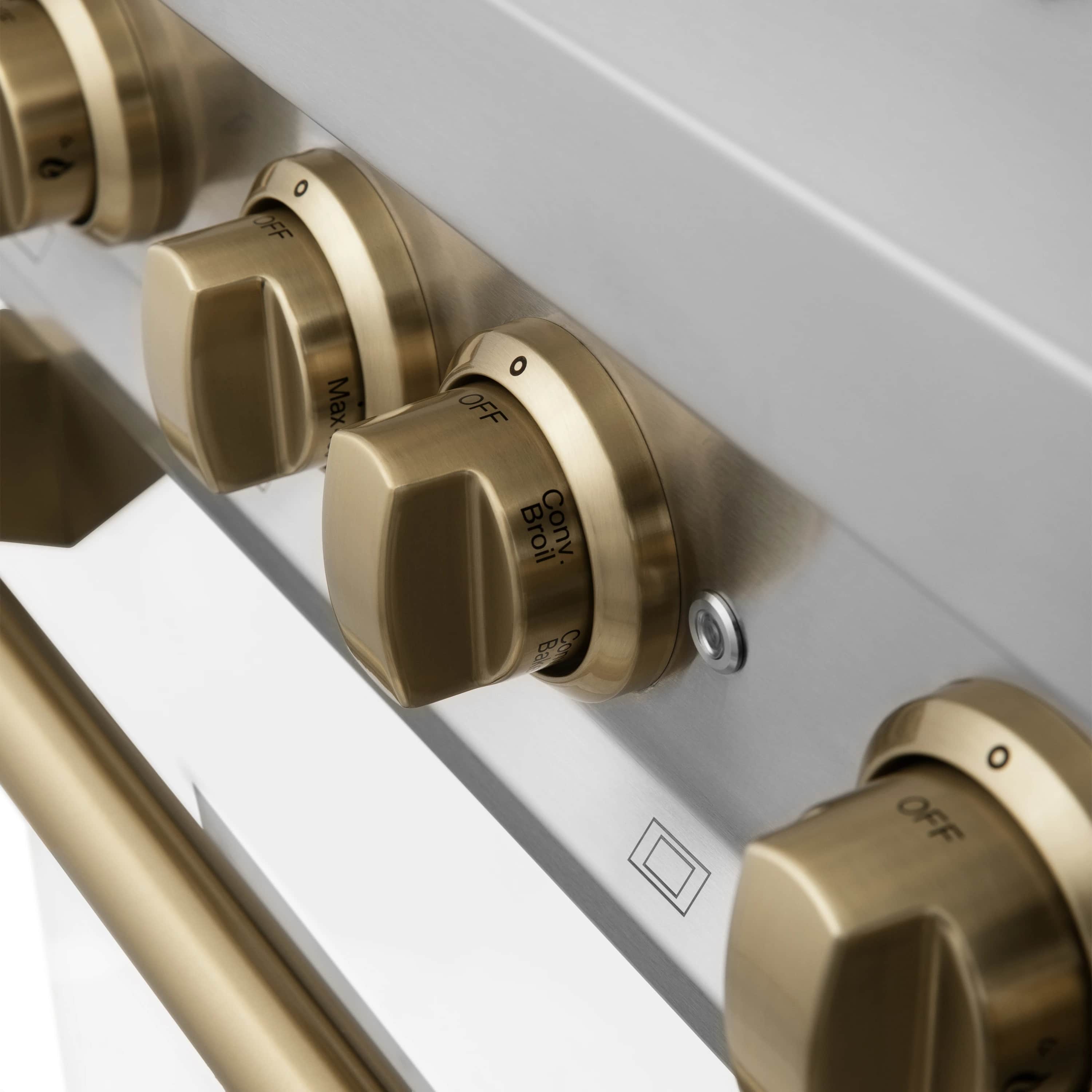Close-up of bronze oven control knobs on a white dual fuel range front