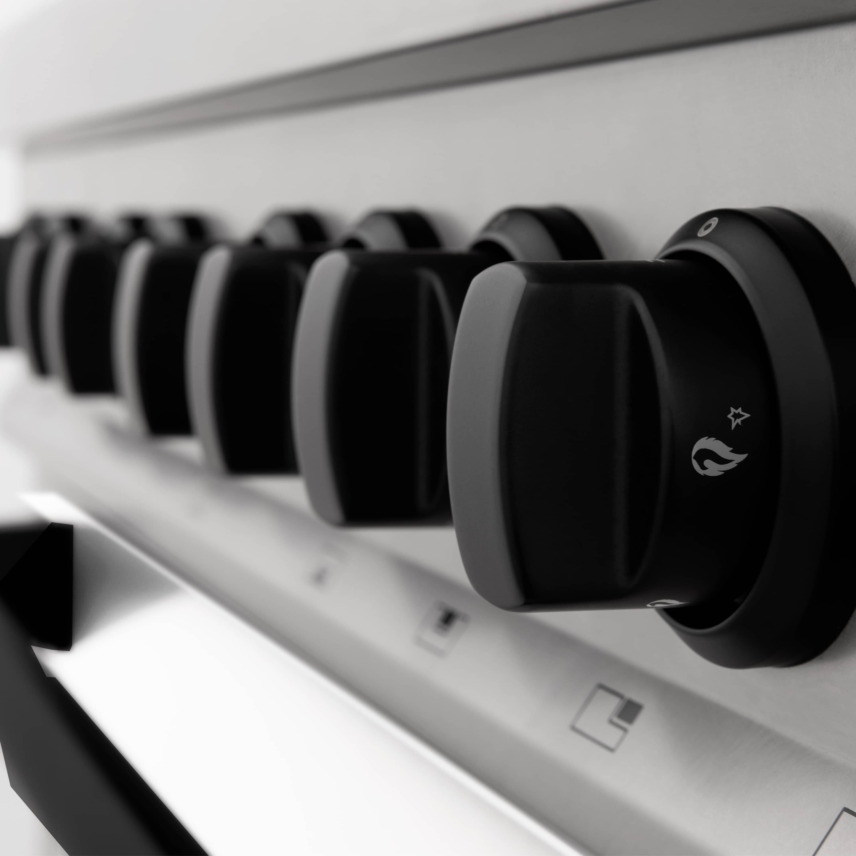 Black burner control knobs row on stainless steel cooktop