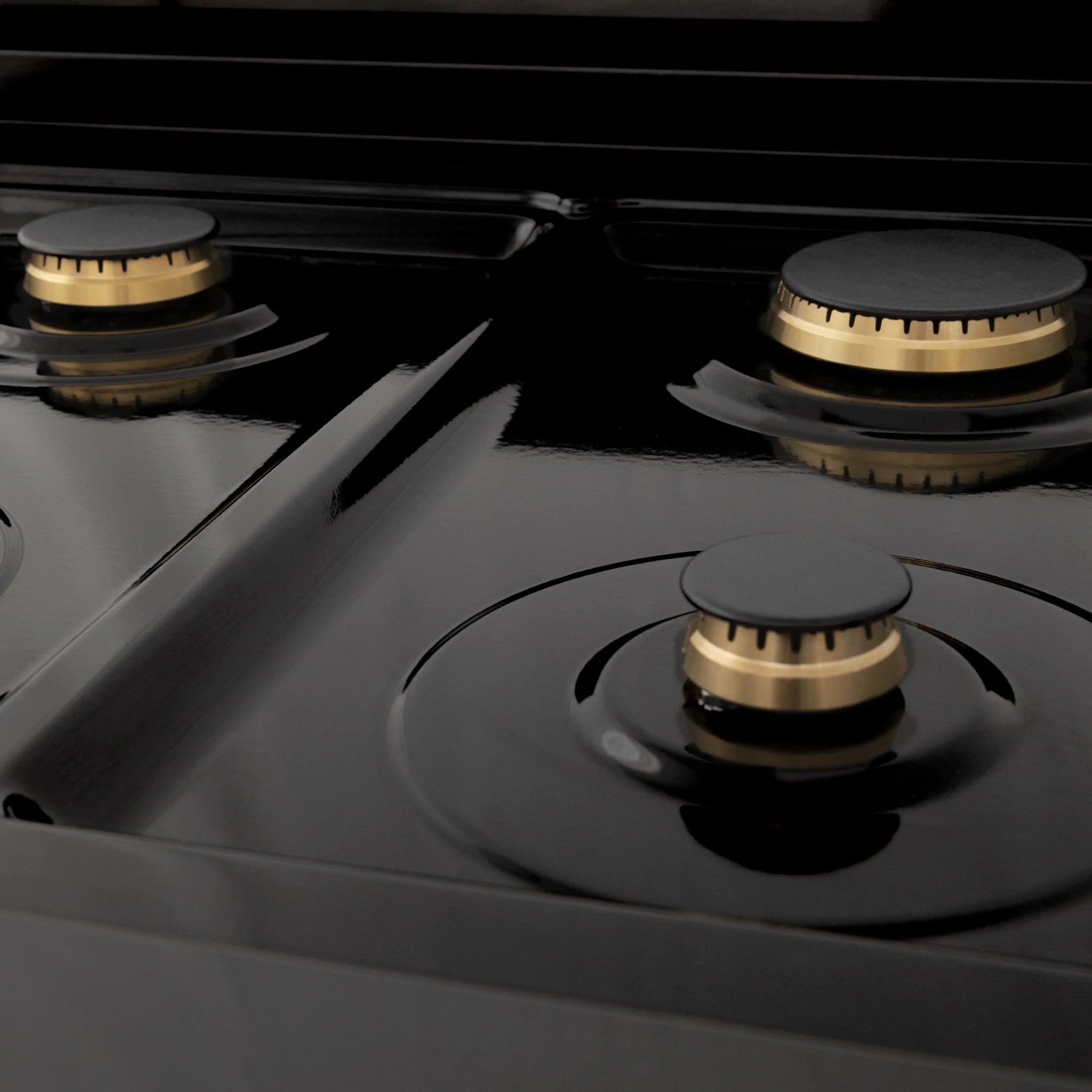 Black cooktop with three brass gas burners and control knobs