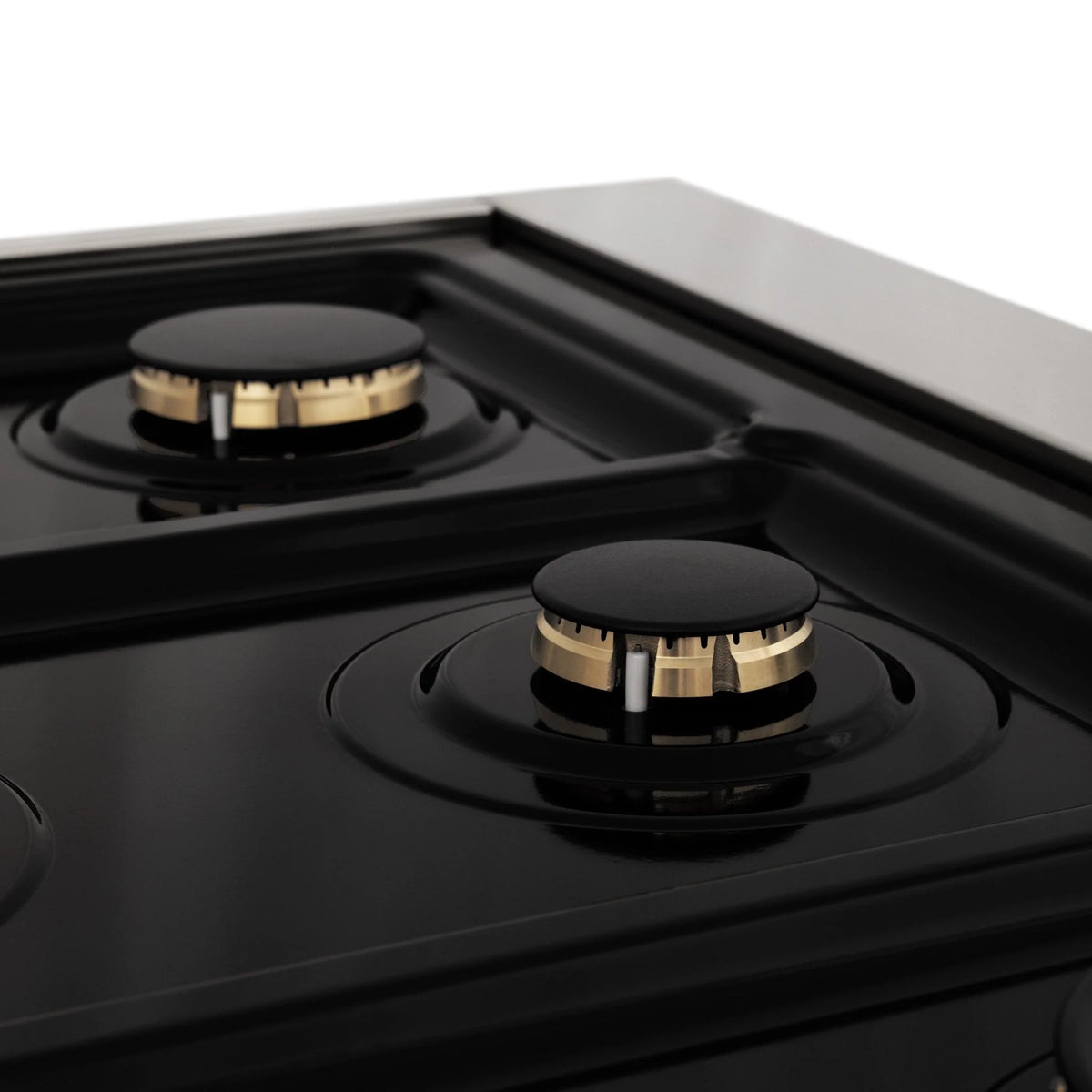 Dual fuel range cooktop with black burners and brass-toned burner caps, side close-up