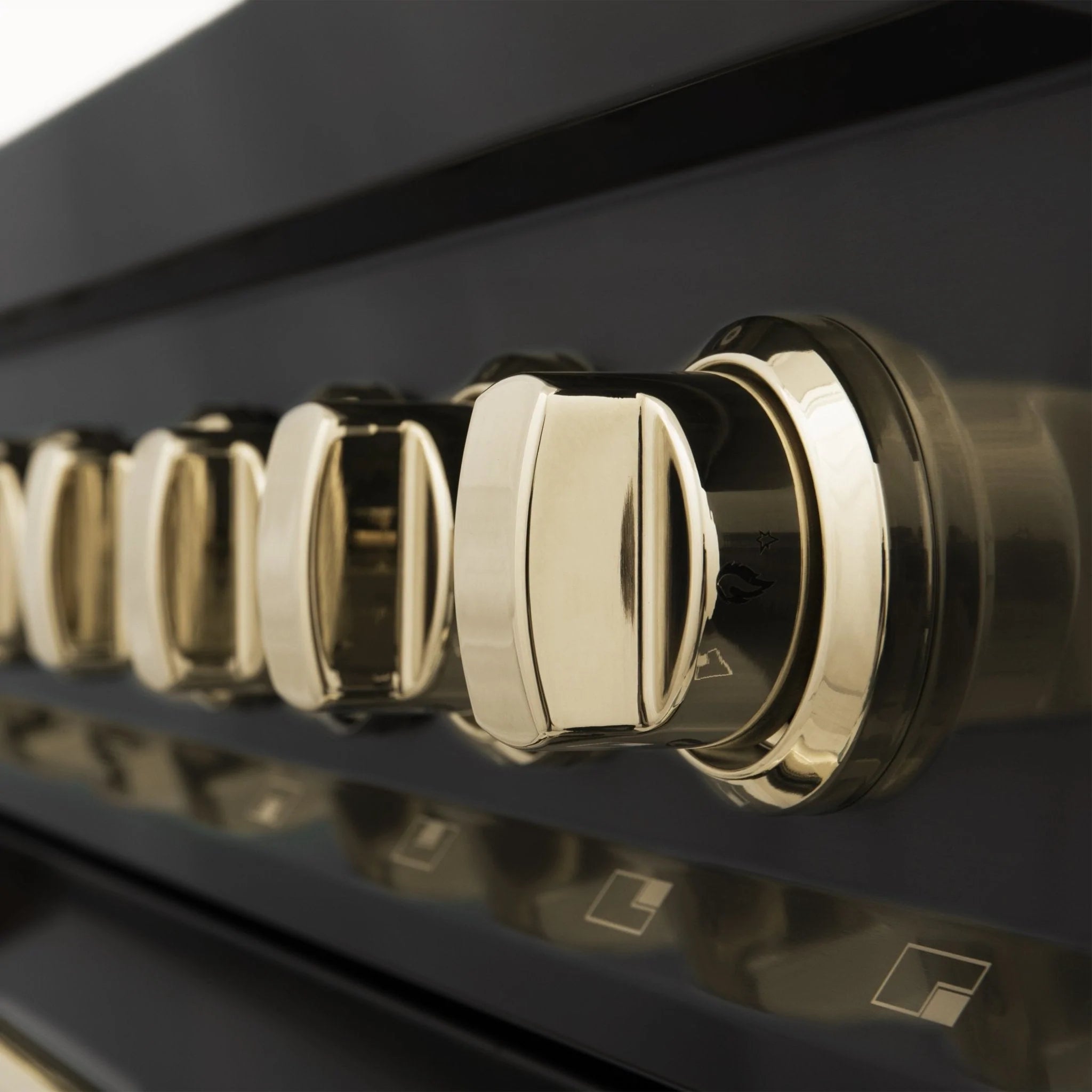 Close-up of gold oven knobs on a black glass control panel.