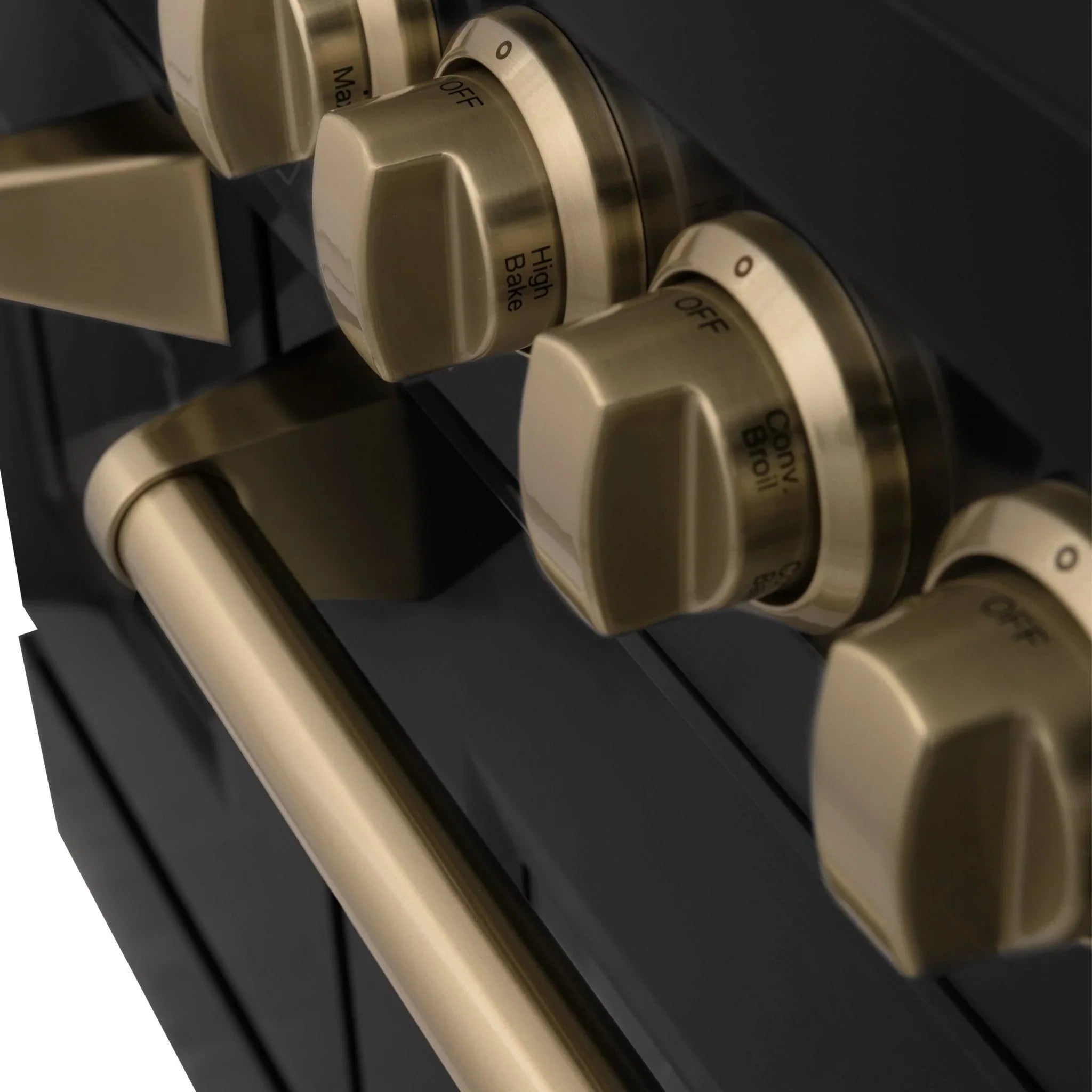 Close-up of champagne bronze control knobs on a black dual-fuel range