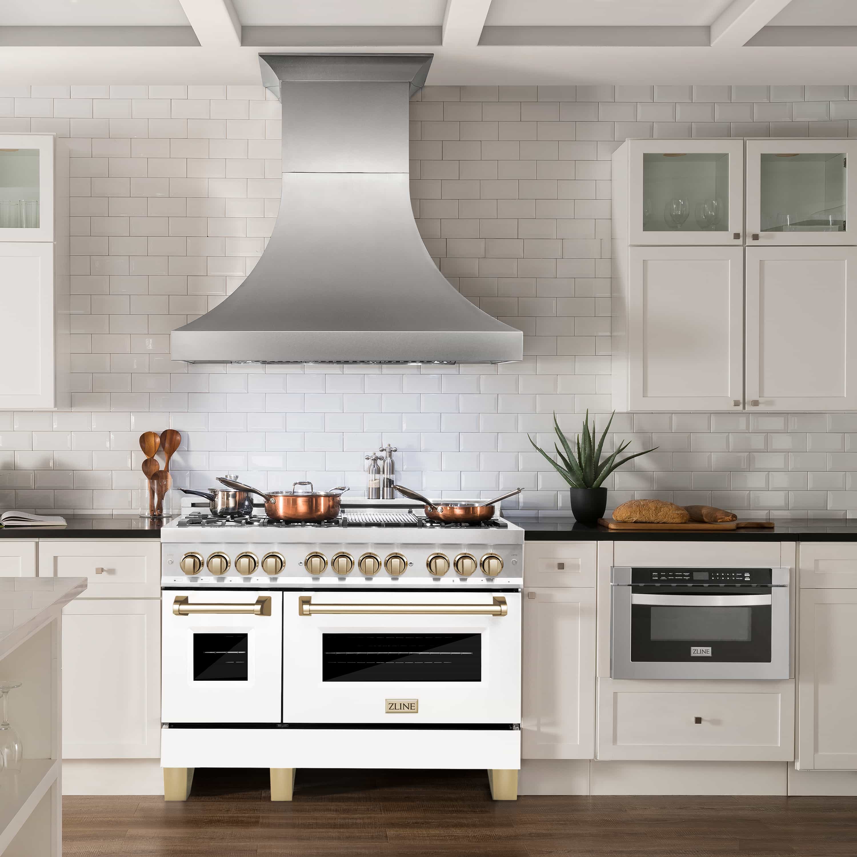 White dual fuel range with gold knobs, brass handles, and black oven doors