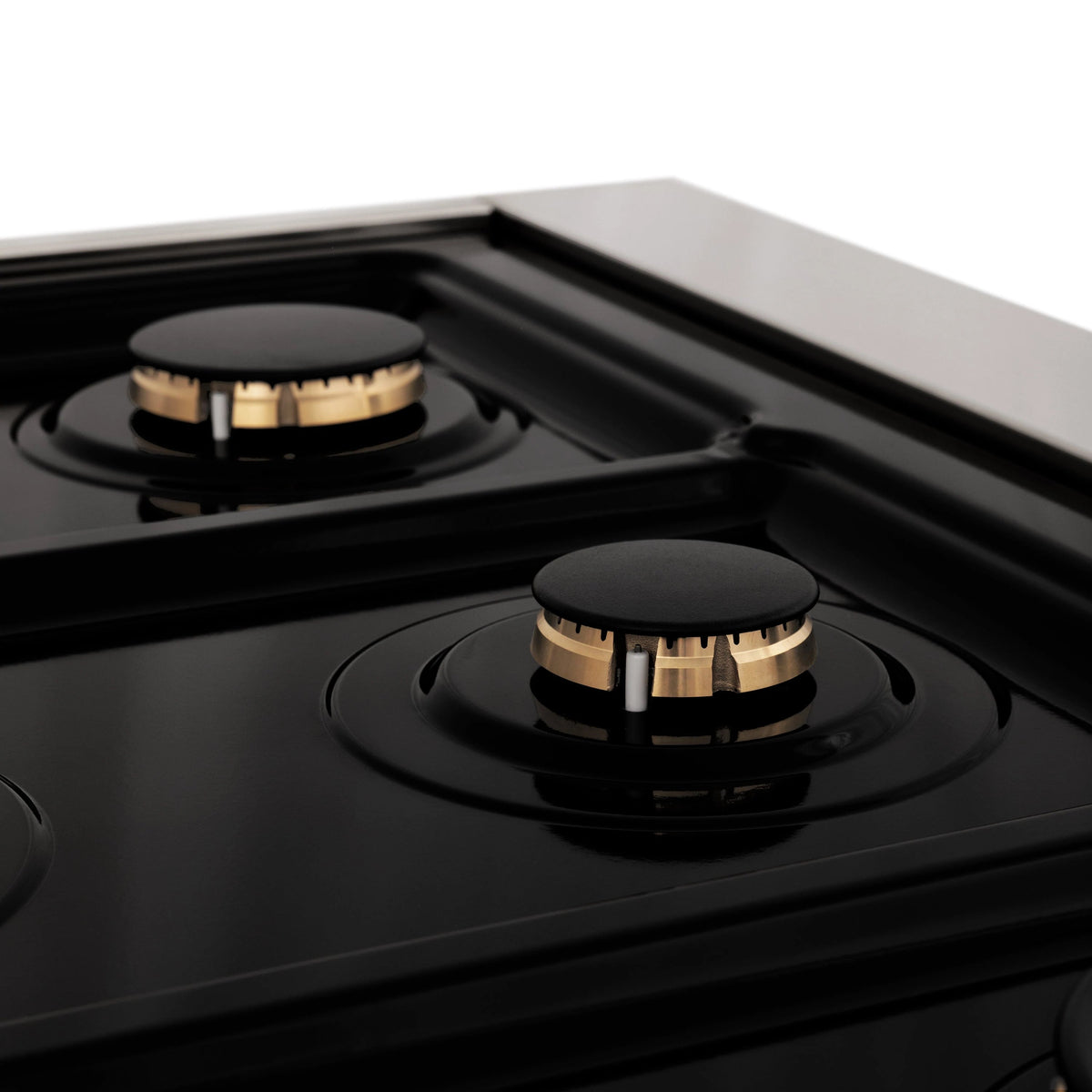 Gas burner detail on black cooktop with bronze accent cap and grate