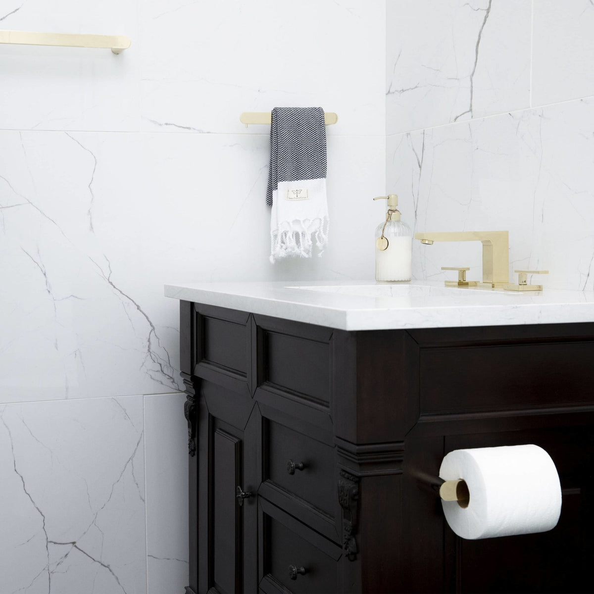 Polished gold bath faucet with spout and two handles on white countertop