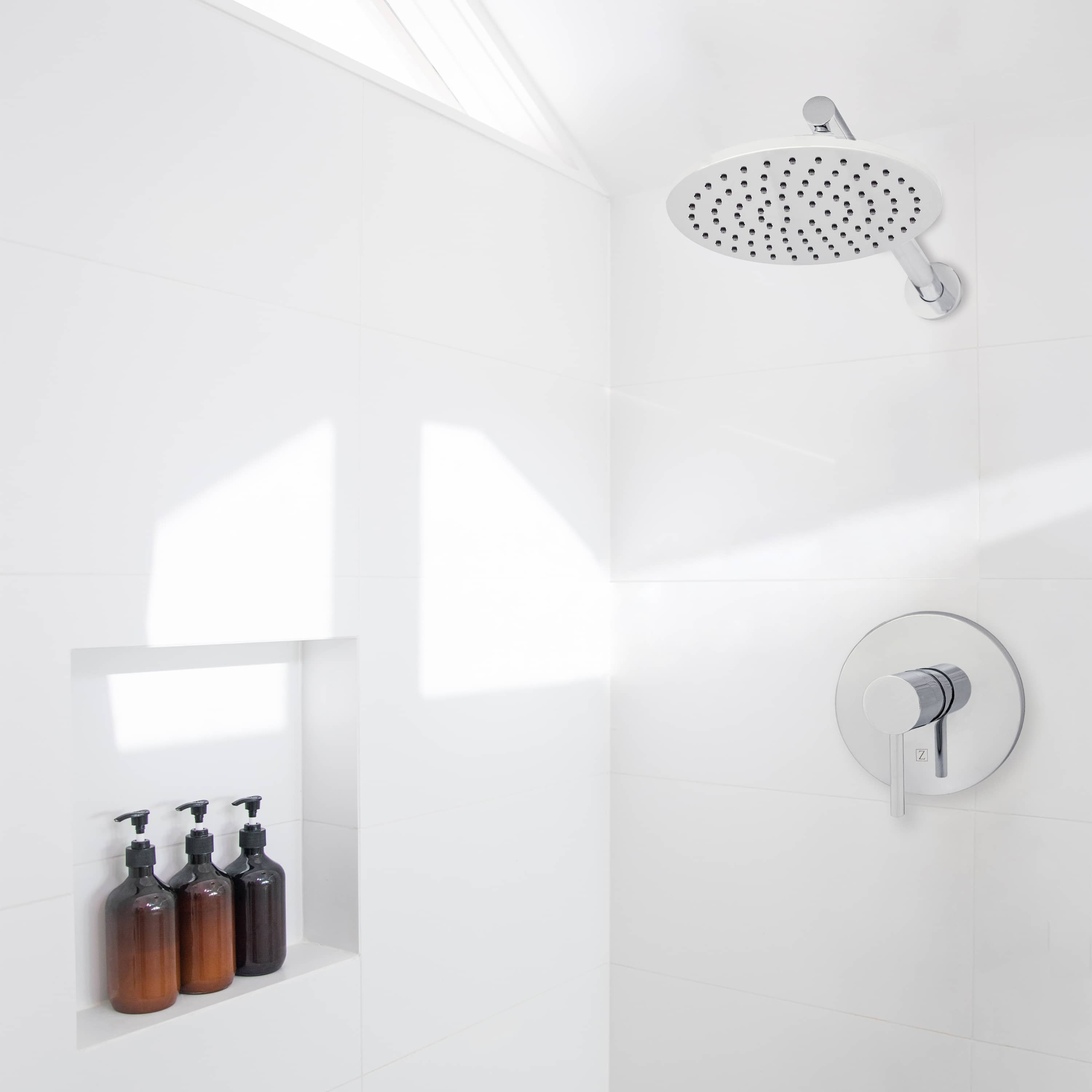 Chrome overhead shower head and matching control valve on a tiled shower wall