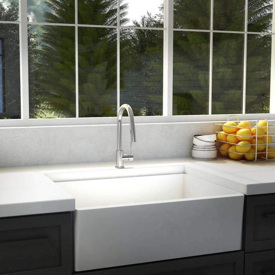Chrome kitchen faucet in a white farmhouse-style sink with tall arched spout
