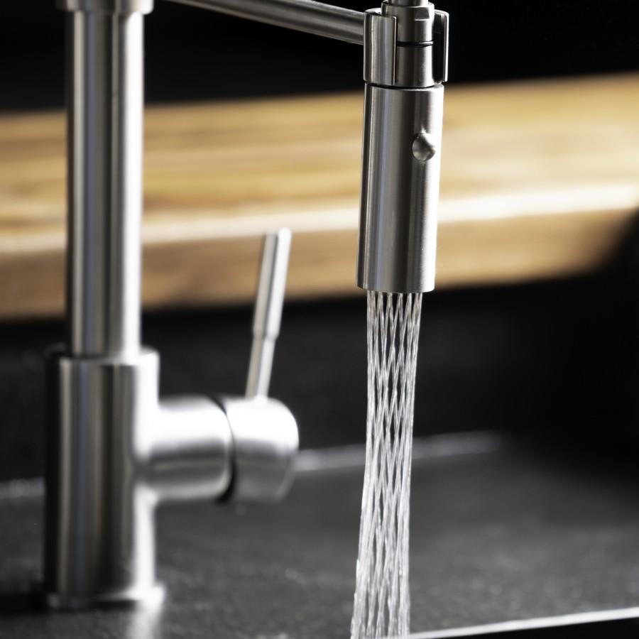 Matte black kitchen faucet with pull-down sprayer releasing a water stream