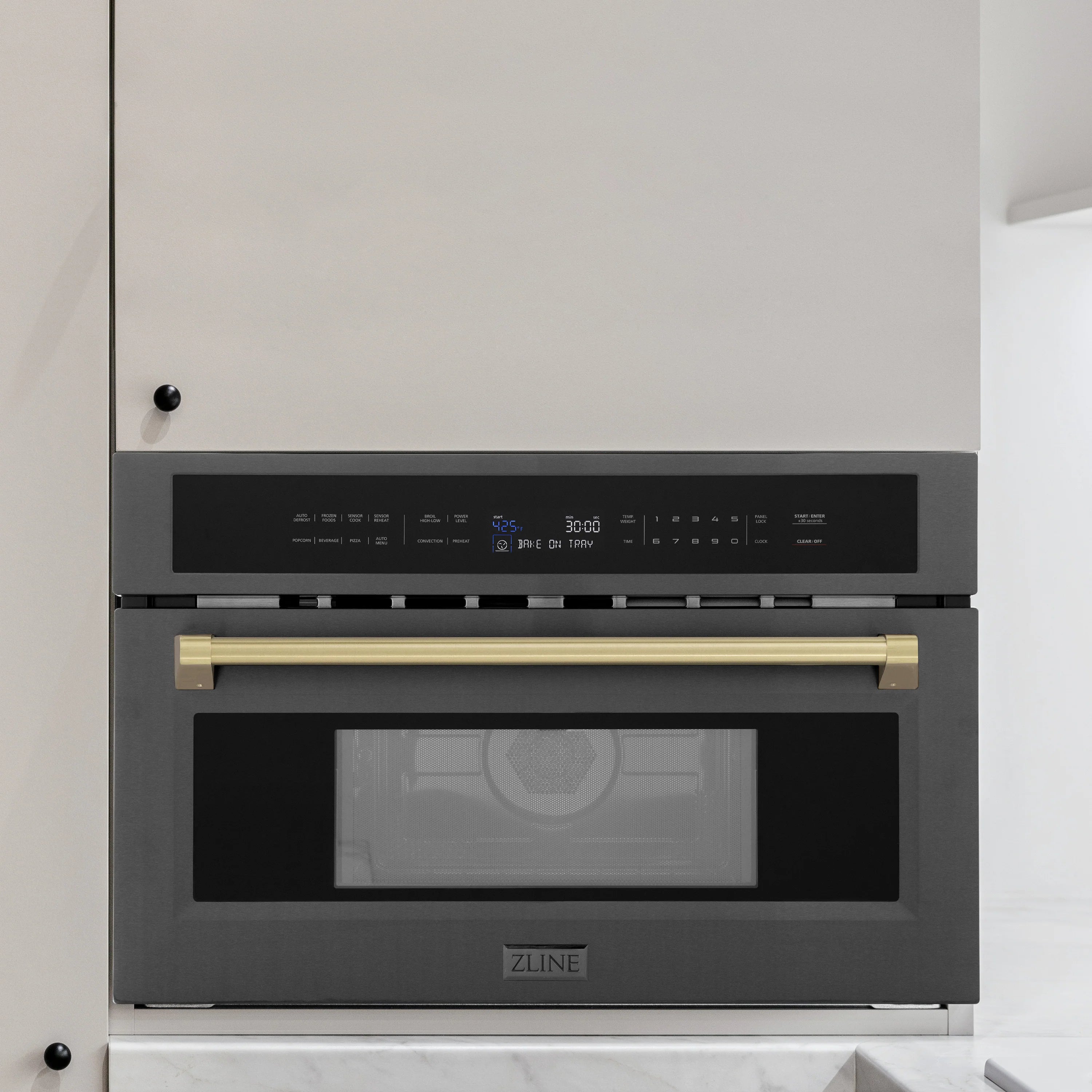 Built-in convection microwave oven front view in light cabinetry, black stainless, bronze handle