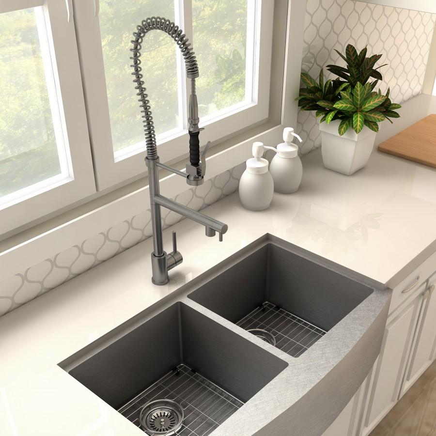 Gun metal kitchen faucet over double sink with tall arched spout and coiled sprayer hose